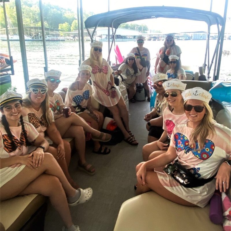 Group of women on a boat wearing nautical-themed hats and swimsuits.