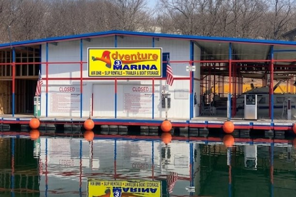 Floating marina shop with signs for beer and boat rentals on a calm lake.